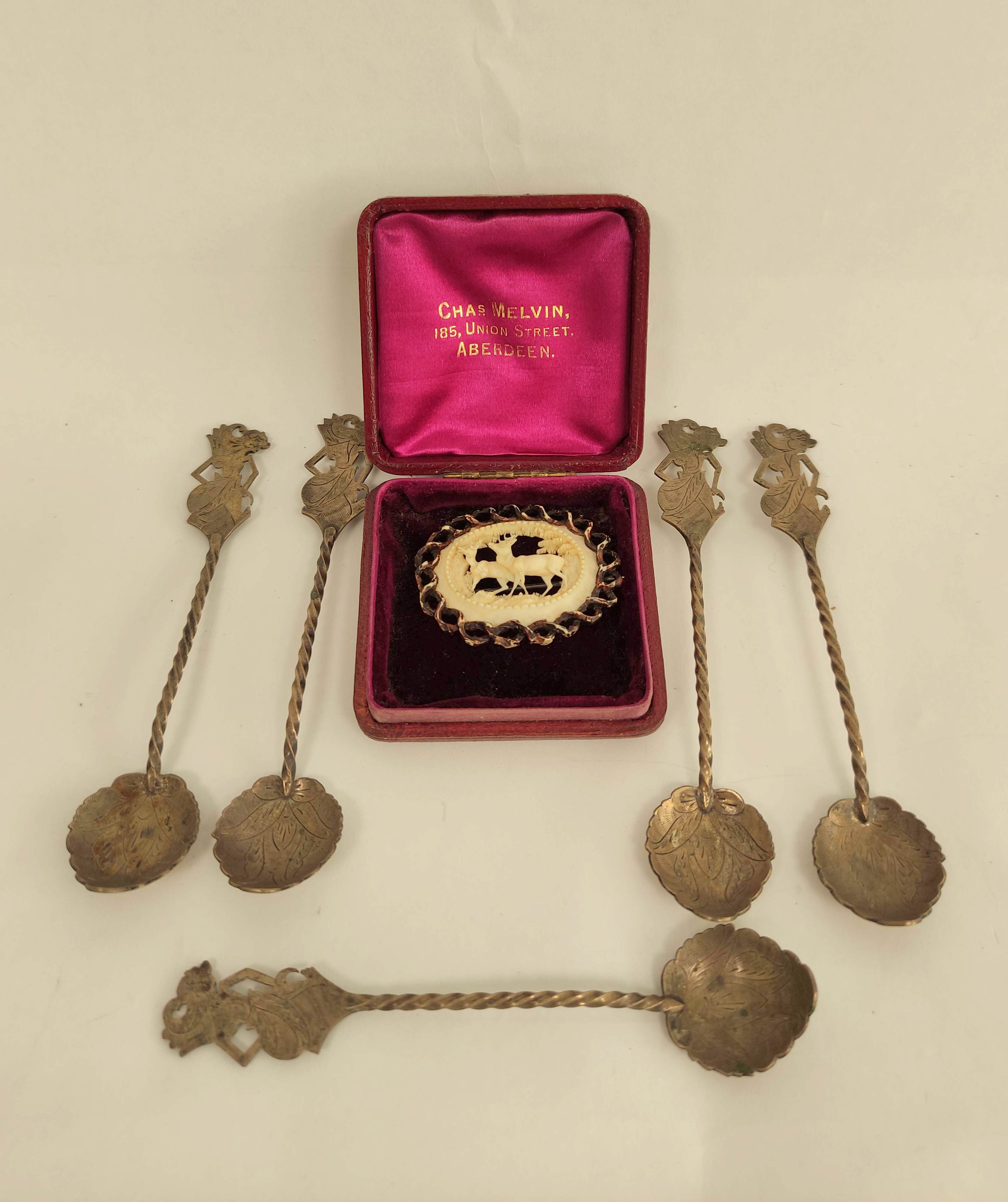 Five Indonesian silver coffee spoons and a delicately carved ivory brooch depicting a deer.