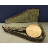 Antique George Formby banjolele in defective leather case. Twenty centimetre diameter head.