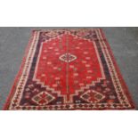 Afghan Belouch hand-knotted rug decorated with a geometric medallion to the centre, on a red ground,