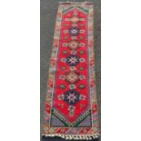 Turkish runner decorated with six central geometric medallions on a red ground, further geometric