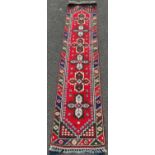 Turkish runner decorated with six central geometric medallions on a red ground, further geometric