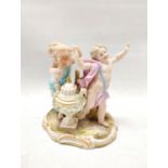 19th century Meissen porcelain figure group of two putti playing with a mask standing on a plinth