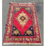 Turkish hand-knotted rug decorated with a central geometric medallion on a red ground, with floral