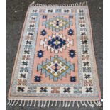 Turkish hand-knotted rug decorated with three geometric medallions to the centre, on a pink
