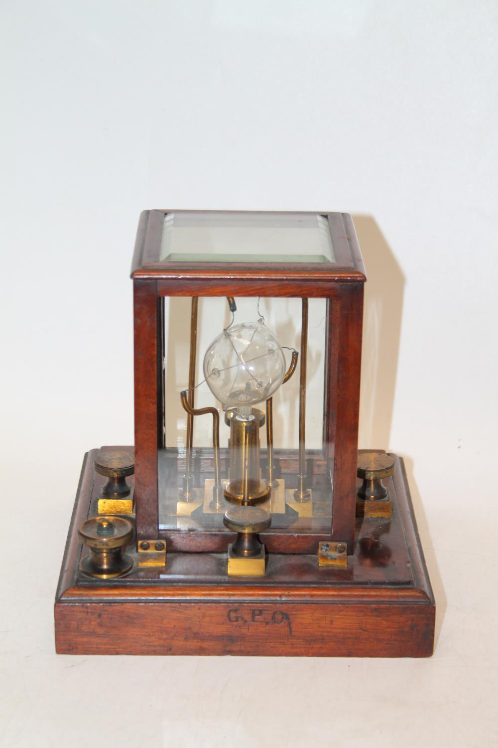 A General Post Office electrical instrument with central bulb housed in a mahogany case stamped GPO,