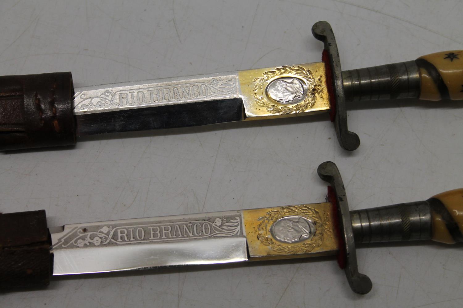 Pair of South American hunting knives, the ricasso marked "Rio Branco", in leather sheaths, blade - Image 2 of 2