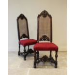 A pair of 17th century style Carolean walnut hall chairs, with carved foliate crest above a