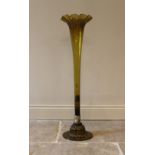 A tall yellow/olive glass vase, 20th century, of trumpet form with shaped rim, set in a white