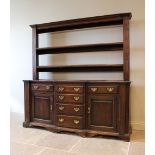 A George III oak North Walian breakfront dresser, the open plate rack with a moulded cornice above