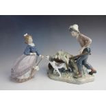 A Lladro figure of a boy pushing a wheelbarrow with his dog beside him, blue printed mark, 22cm