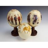 Two printed ostrich eggs, one decorated with Zulu warriors and text 'Zulu War' and '1879', the other