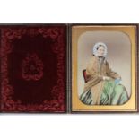 A Victorian cased watercolour portrait of a seated lady in a lace bonnet holding a book, mid 19th