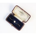 A cultured pearl set bar brooch, the central round cultured pearl measuring 6mm diameter, set to a