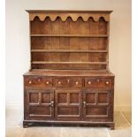 A George III oak dresser, the later associated plate rack with a scalloped frieze and three shelves,