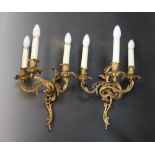 A pair of French ormolu Rococo style three branch wall sconces, cast as three intertwined foliate