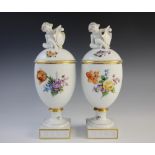 A pair of Copenhagen urns and covers, each decorated in polychrome enamels with floral sprays within