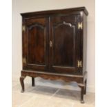 A mid 18th century oak cabinet on stand, the moulded cornice above two fielded panel doors and a