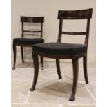 A pair of Regency mahogany dining chairs, each with a concave rail above a stuff over seat, raised