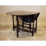 An 18th century and later oak drop leaf table, the oval plank top raised upon block and barley twist