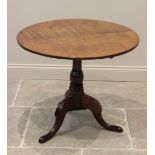 A George III oak tripod table, the circular top raised upon a ring turned baluster column, extending