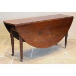 A George III oval drop leaf table, the mahogany top raised upon associated oak legs of tapering