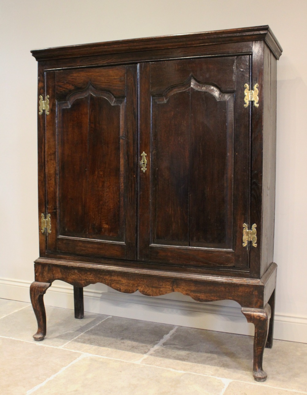 A mid 18th century and later oak cabinet on stand, the moulded cornice above two fielded panel doors