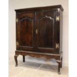 A mid 18th century and later oak cabinet on stand, the moulded cornice above two fielded panel doors