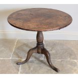 A George III oak tripod table, the circular top raised upon a baluster column extending to three