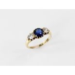 An Edwardian sapphire and diamond three stone ring, comprising a round mixed cut sapphire