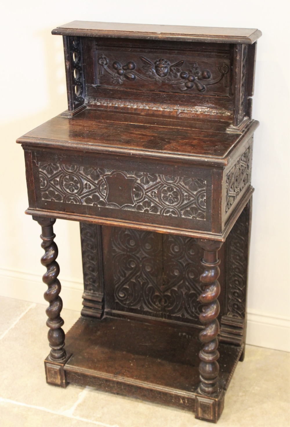 A 17th century and later carved oak hall stand, the raised back upon an early hinged bible box,