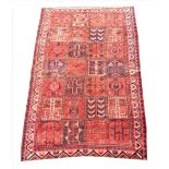 A red ground vintage Bakhtiari region carpet, the central panel with twenty eight alternating
