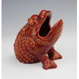 A Burmantofts faience spoon warmer, modelled as a grotesque bull frog in a burnt red/orange glaze,