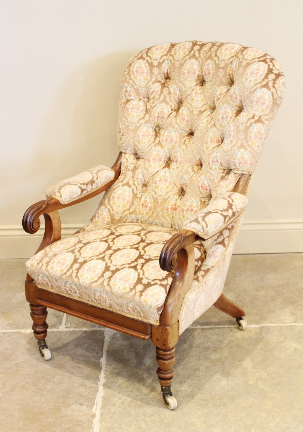 A Victorian upholstered mahogany drawing room chair, the arched button back extending to padded