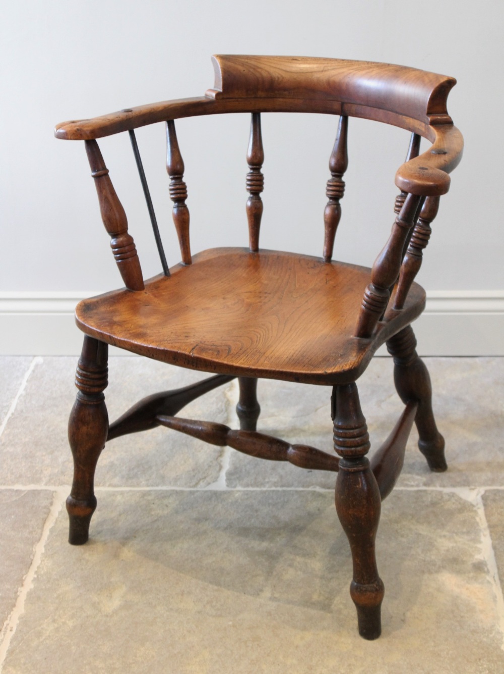 A late 19th century elm and beech smokers bow elbow chair, the 'C' shaped top rail raised upon