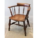 A late 19th century elm and beech smokers bow elbow chair, the 'C' shaped top rail raised upon