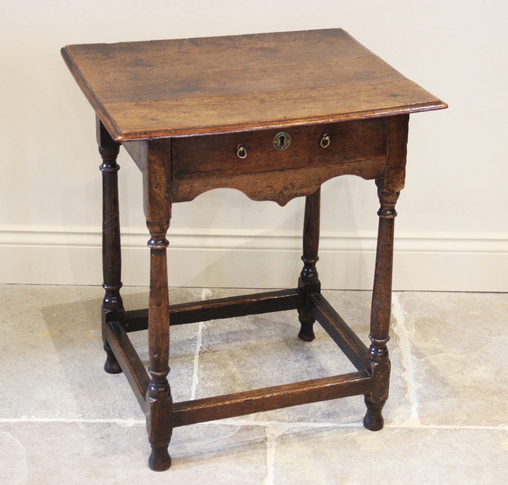 An 18th century oak side table, of cottage proportions, the rectangular moulded top raised upon ring