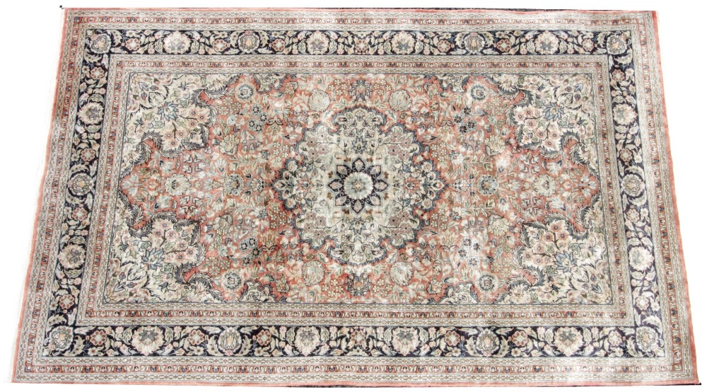 A Persian pattern silk work rug, the foliate medallion design upon a pale red ground, within a