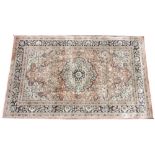 A Persian pattern silk work rug, the foliate medallion design upon a pale red ground, within a