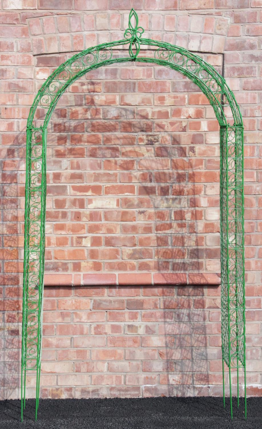 A painted metal wire work garden arch, the scrolling and lattice work frame extending to spiked