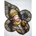 A quatrefoil stained glass portrait panel depicting an ecclesiastical figure in ceremonial