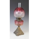 A Victorian brass and cranberry glass oil lamp, 19th century, the cast brass base of pyramidal