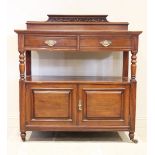 A late Victorian walnut dumb waiter, with a scrolling leaf carved pediment over two frieze
