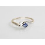 A diamond and sapphire two-stone ring, comprising a round mixed cut diamond (measuring 3.5mm