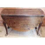 A mid 18th century oval oak drop leaf dining table, with a shaped frieze upon cabriole legs and