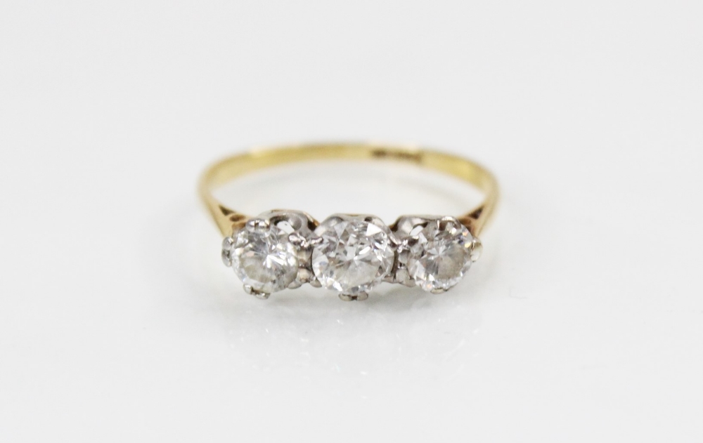 A diamond three stone ring, comprising a central round brilliant cut diamond (weighing approximately