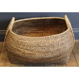 A wicker basket of large proportions, of swelling lozenge form with loop handle to each end,