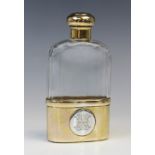 An Edwardian silver gilt and glass hip flask by Finnigans Ltd, London 1904, the faceted bottle