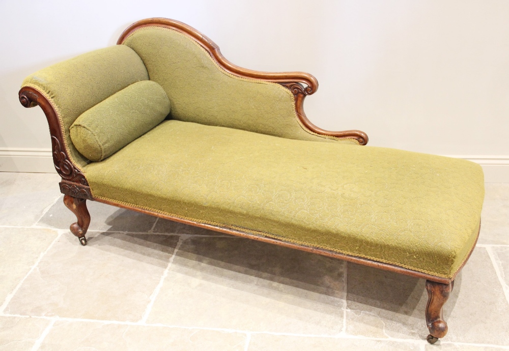 A Victorian mahogany framed chaise longue, the shaped padded back extending to swept and scrolled