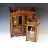 An early 20th century oak smokers cabinet, the carved pediment above a pair of glazed doors