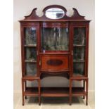 An Edwardian inlaid mahogany display cabinet, the mirrored pediment over a central concave glazed